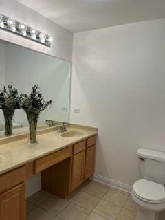 bathroom with tile patterned flooring, toilet, double vanity, and baseboards