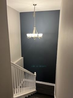 stairway with baseboards and a chandelier