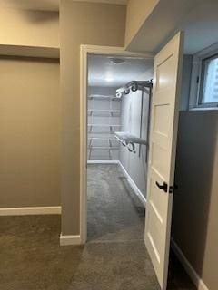 walk in closet with dark colored carpet