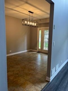 unfurnished dining area featuring baseboards and a chandelier
