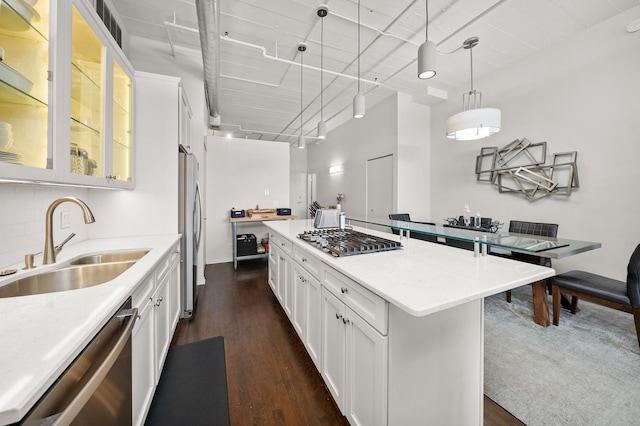 kitchen with a sink, appliances with stainless steel finishes, light countertops, and dark wood finished floors