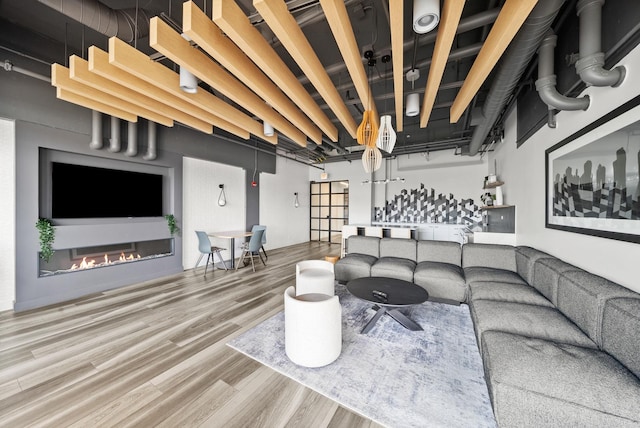 living area with wood finished floors and a glass covered fireplace