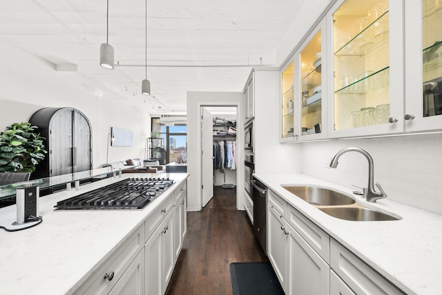 kitchen with a sink, appliances with stainless steel finishes, backsplash, and light stone countertops