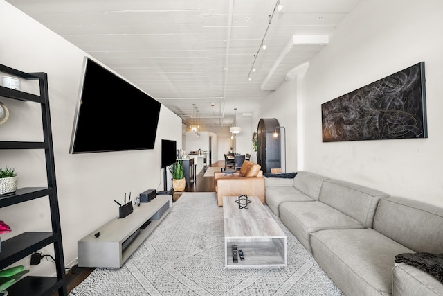 living area with arched walkways, track lighting, and wood finished floors