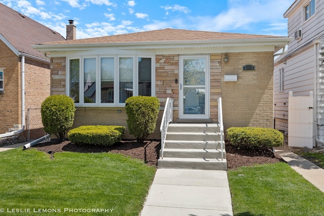 3309 N Ozanam Ave, Chicago, IL 60634 - view of exterior entry with a lawn, roof with shingles, a chimney, and brick siding