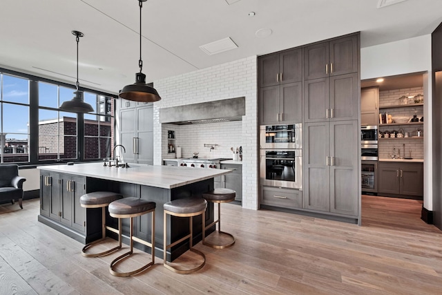 1109 W Washington Blvd Unit 5C, Chicago, IL 60607 - kitchen with decorative backsplash, light wood-type flooring, a sink, and a kitchen breakfast bar