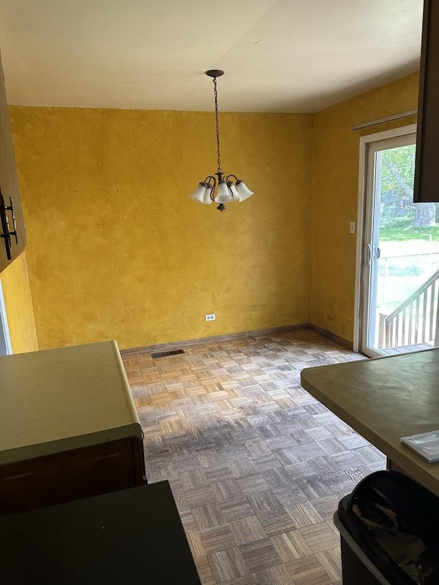 unfurnished dining area featuring a chandelier and baseboards
