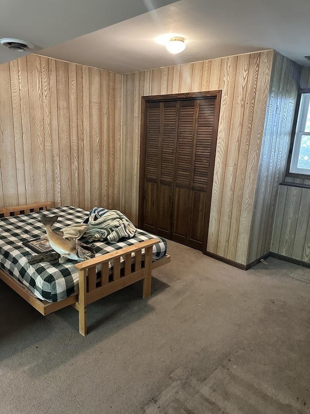 carpeted bedroom with wooden walls and a closet