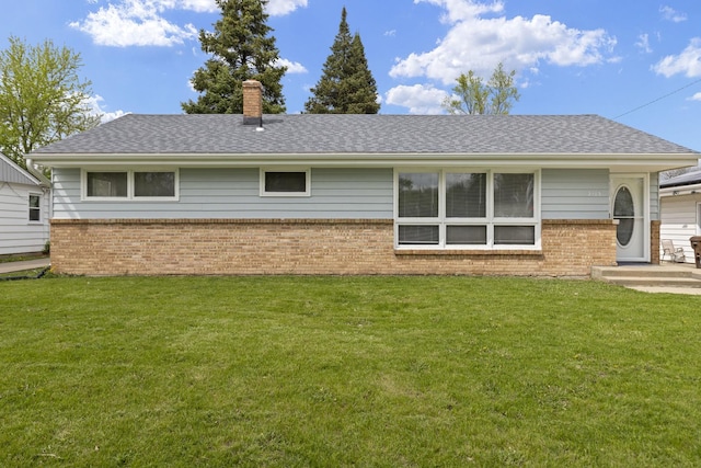back of house featuring brick siding, a yard, a chimney, and a shingled roof