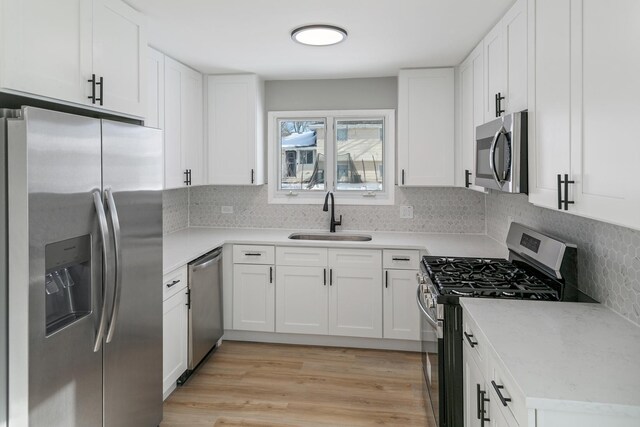 22751 Redwood Dr, Richton Park, IL 60471 - kitchen featuring appliances with stainless steel finishes, a sink, white cabinets, tasteful backsplash, and light wood-style flooring