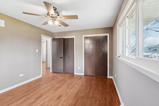 6709 W Menominee Pkwy, Palos Heights, IL 60463 - unfurnished bedroom with two closets, light wood finished floors, baseboards, and a ceiling fan