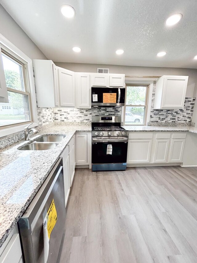 384 N Grand Ave, Bradley, IL 60915 - kitchen with appliances with stainless steel finishes, a sink, decorative backsplash, white cabinetry, and light wood-type flooring