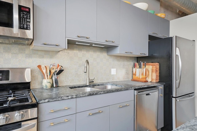 kitchen featuring stainless steel appliances, a sink, gray cabinets, and backsplash