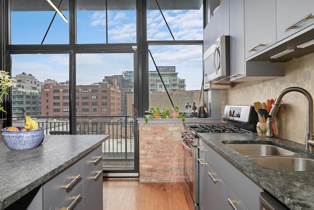 kitchen with stainless steel appliances, gray cabinetry, a sink, and healthy amount of natural light