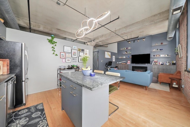 kitchen featuring light wood-style floors, a breakfast bar area, a kitchen island, stainless steel appliances, and decorative light fixtures