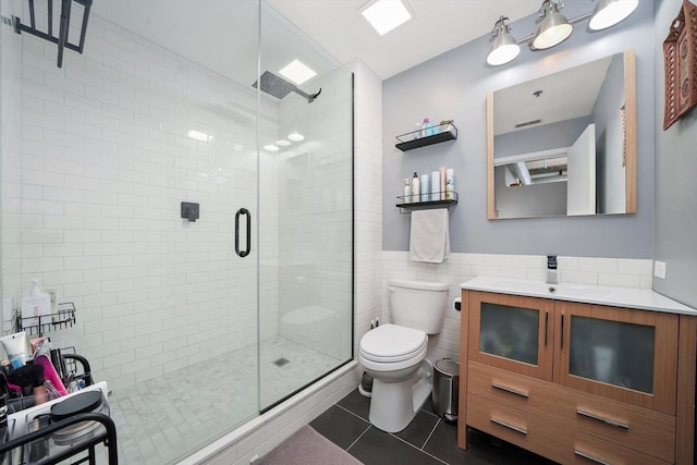 full bathroom with tile patterned flooring, tile walls, toilet, a shower stall, and vanity
