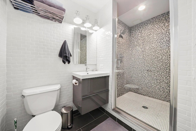 full bathroom featuring tile patterned floors, a stall shower, toilet, tile walls, and vanity
