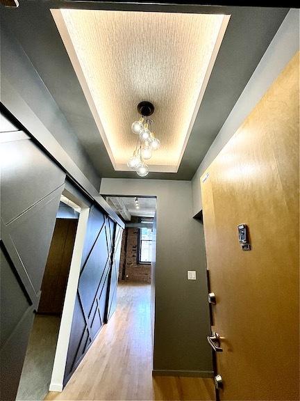 hallway featuring a tray ceiling and wood finished floors