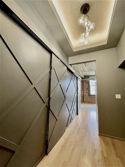 hall with a tray ceiling and light wood-style flooring