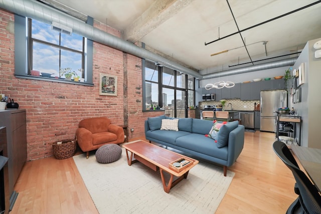 living room with brick wall, light wood-type flooring, and a towering ceiling