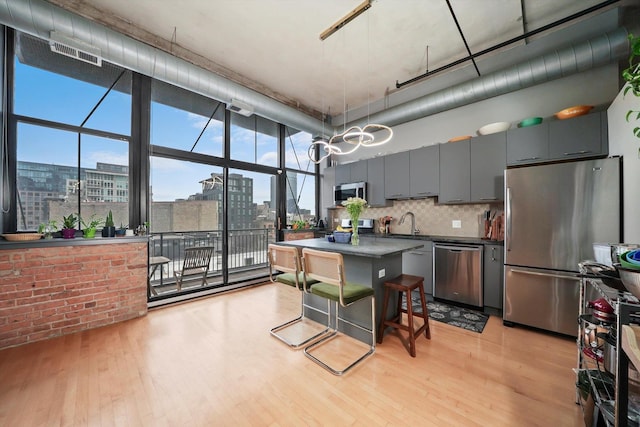 kitchen with stainless steel appliances, dark countertops, a city view, light wood finished floors, and a wall of windows