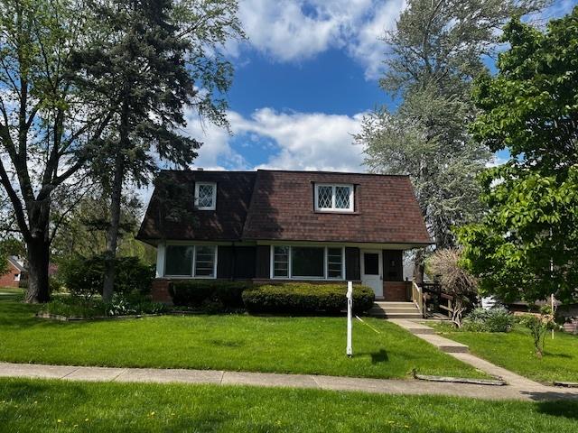 view of front of home featuring mansard roof and a front lawn