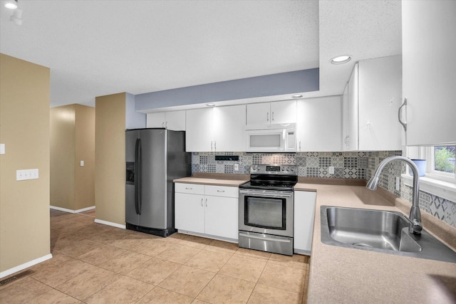 3112 Valerie Dr, Champaign, IL 61822 - kitchen featuring appliances with stainless steel finishes, white cabinets, decorative backsplash, light countertops, and recessed lighting