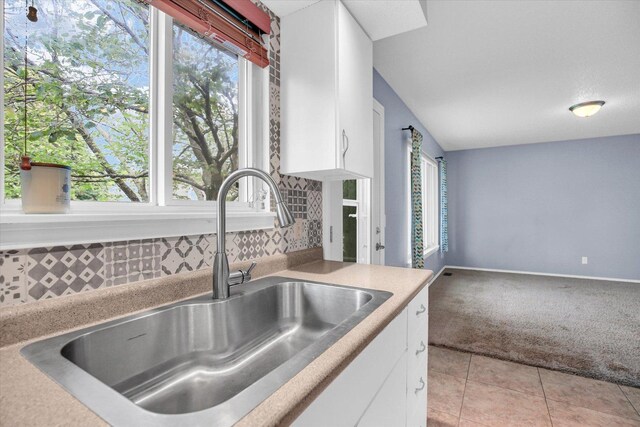 3112 Valerie Dr, Champaign, IL 61822 - kitchen with light colored carpet, white cabinets, tasteful backsplash, light countertops, and light tile patterned floors