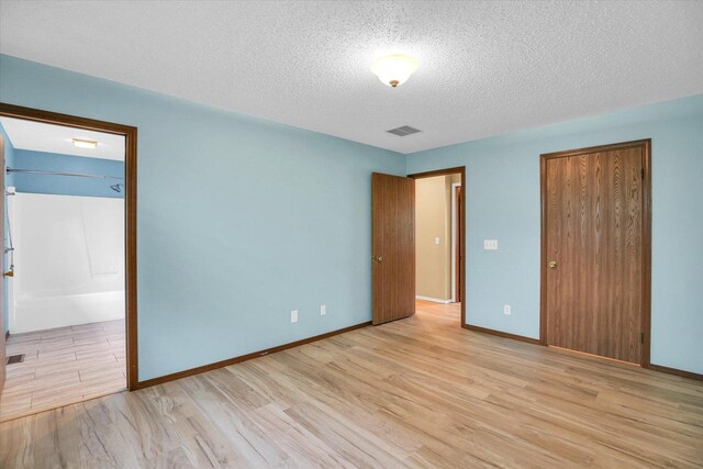3112 Valerie Dr, Champaign, IL 61822 - unfurnished bedroom featuring light wood-type flooring, a textured ceiling, a closet, and ensuite bath
