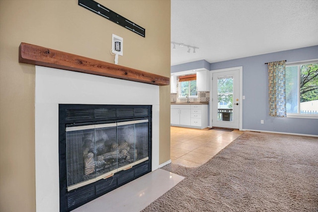 3112 Valerie Dr, Champaign, IL 61822 - unfurnished living room with a fireplace with flush hearth, track lighting, light tile patterned floors, and plenty of natural light