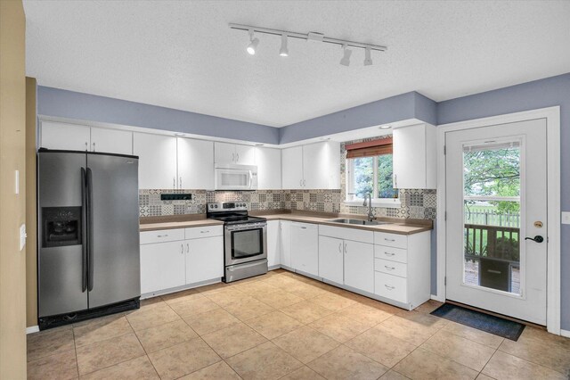 3112 Valerie Dr, Champaign, IL 61822 - kitchen with appliances with stainless steel finishes, backsplash, white cabinets, rail lighting, and light tile patterned floors