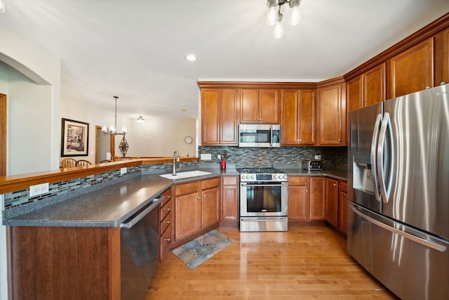 1468 W Remington Ln, Round Lake, IL 60073 - kitchen with stainless steel appliances, a sink, brown cabinetry, a peninsula, and backsplash