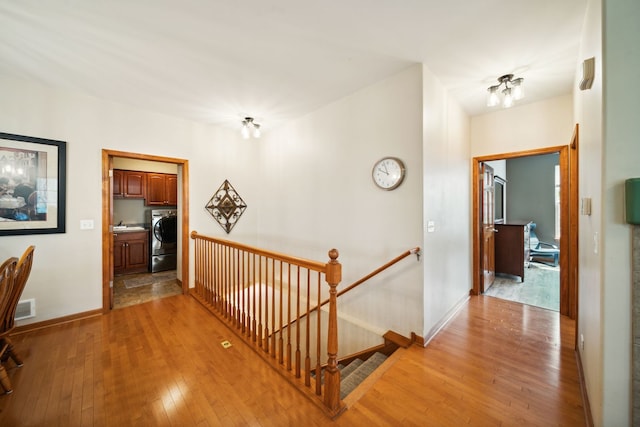 1468 W Remington Ln, Round Lake, IL 60073 - hallway with an upstairs landing, washer / dryer, light wood finished floors, and baseboards