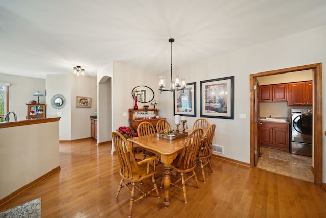 1468 W Remington Ln, Round Lake, IL 60073 - dining space featuring washer / dryer, arched walkways, a chandelier, light wood-style flooring, and baseboards
