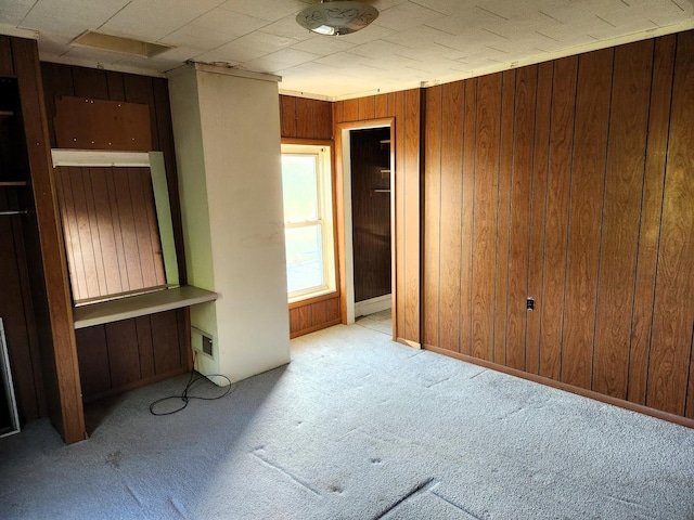unfurnished bedroom with carpet and wood walls