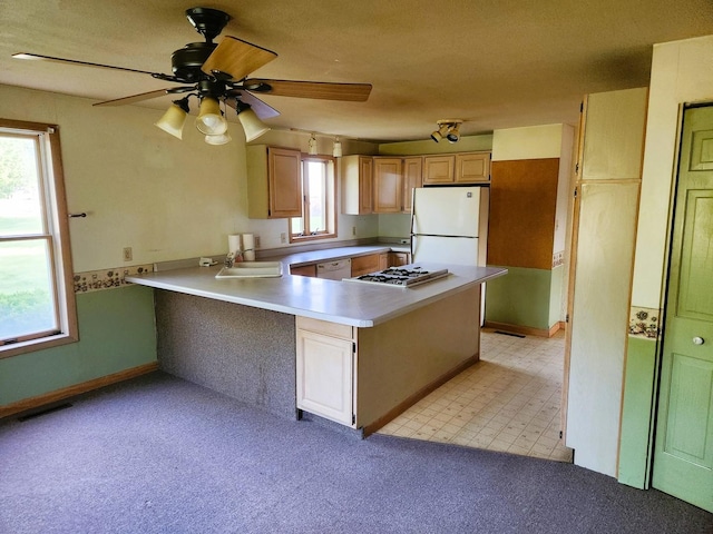 kitchen featuring white appliances, ceiling fan, a peninsula, a sink, and light countertops
