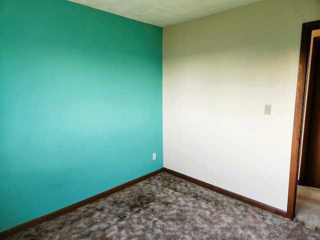 spare room with dark colored carpet and baseboards