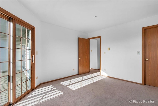 carpeted empty room featuring healthy amount of natural light and baseboards