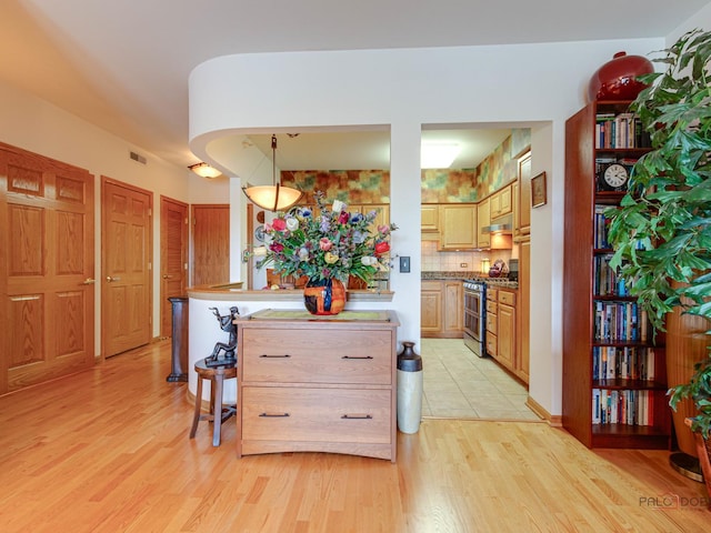 5 W Central Rd Unit 512, Mount Prospect, IL 60056 - kitchen featuring stainless steel gas range oven, light wood finished floors, decorative backsplash, and hanging light fixtures