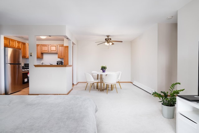 dining space with a baseboard radiator, a ceiling fan, light colored carpet, and baseboards