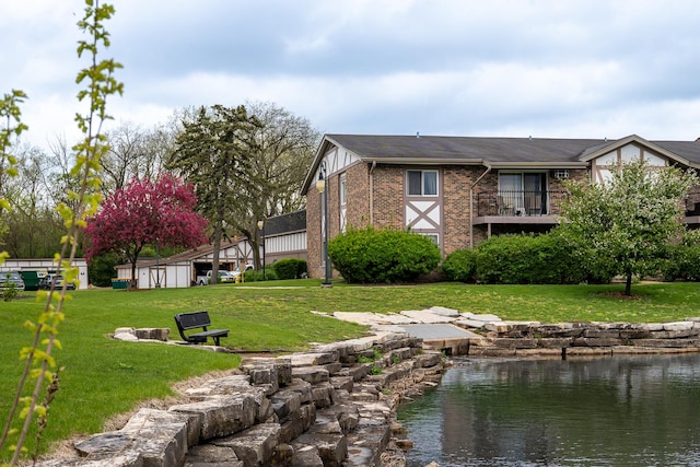 view of side of home with a water view, a lawn, and brick siding