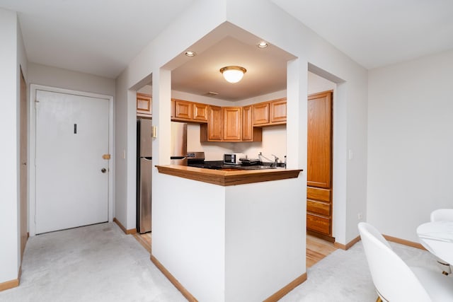 kitchen featuring recessed lighting, baseboards, light colored carpet, stainless steel appliances, and a sink