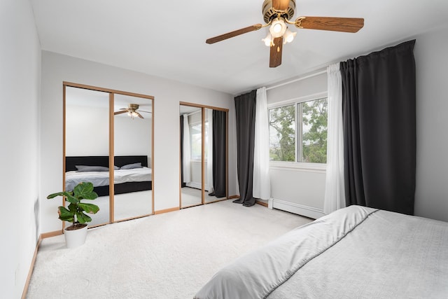 carpeted bedroom with a baseboard radiator, multiple closets, and baseboards