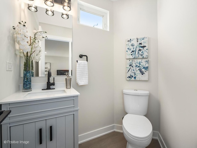 bathroom featuring baseboards, toilet, vanity, and wood finished floors