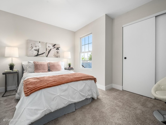 carpeted bedroom with a closet and baseboards
