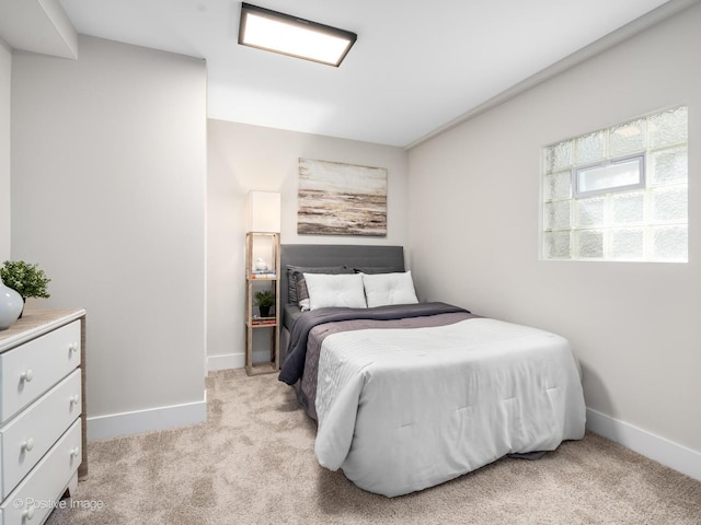 bedroom with light colored carpet and baseboards