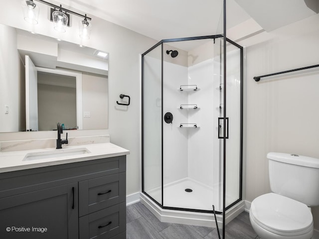 full bathroom featuring a stall shower, toilet, vanity, and baseboards