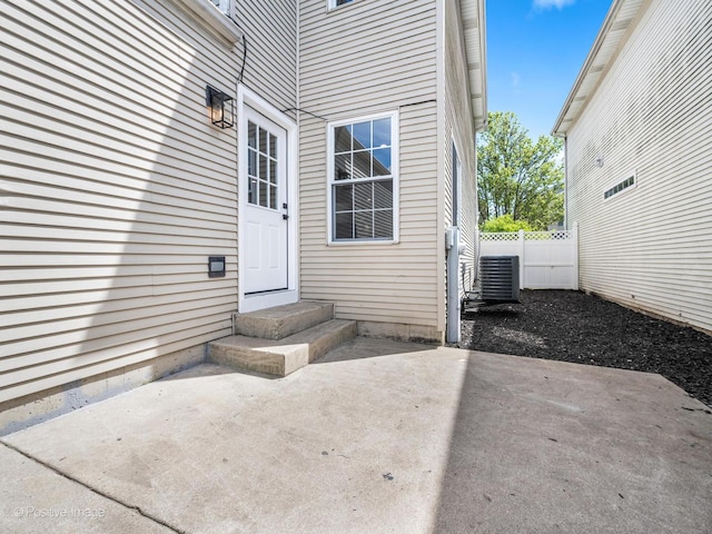 property entrance with a patio, cooling unit, and fence