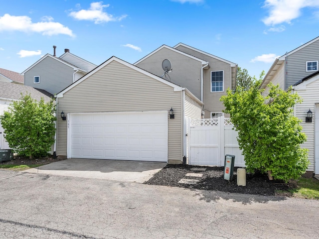 traditional-style house with an attached garage, fence, and concrete driveway