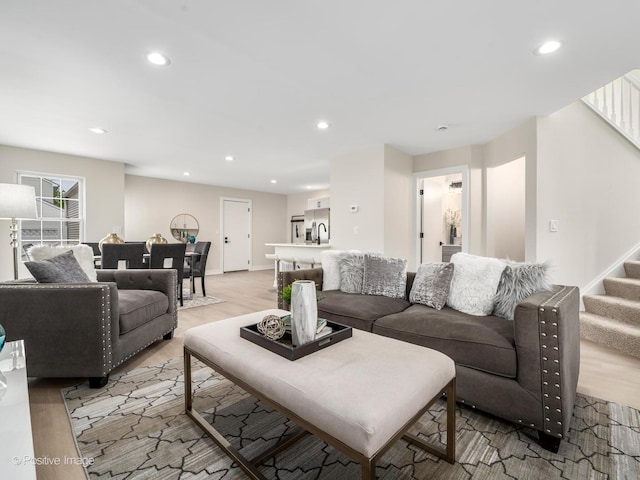 living room featuring stairs, recessed lighting, light wood-type flooring, and baseboards